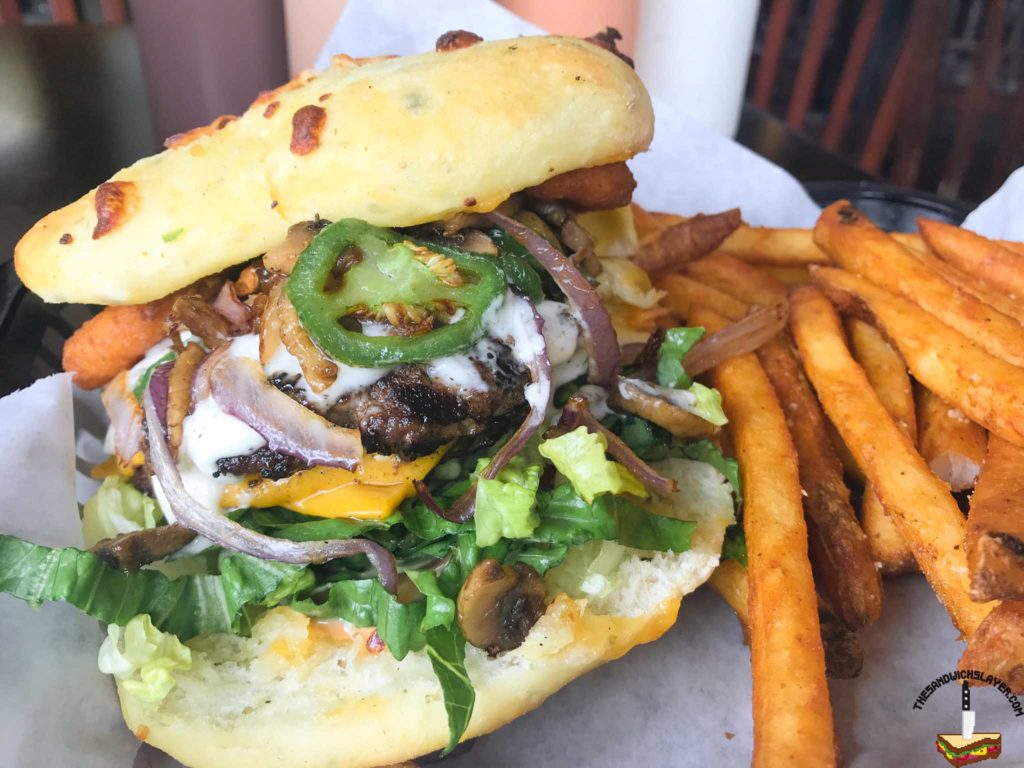 Rockfire grill's OMG burger with onion rings, cheddar cheese, mushroom, garlic aioli and lettuce on house baked flatbread